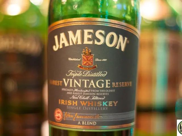 In this image I can see a wine bottle with green color and a sticker with grey color is attached to...